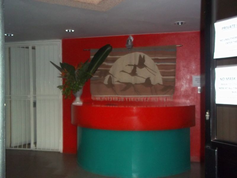 Commercial entry area featuring a built-in reception desk, security gate, and recessed lighting, currently showing dated finishes.