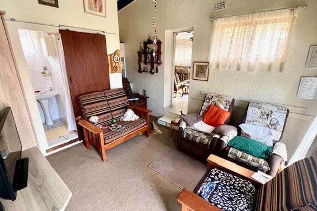 A living area featuring carpeted flooring, a sliding door leading to an en-suite bathroom, and access to an adjacent dining space.