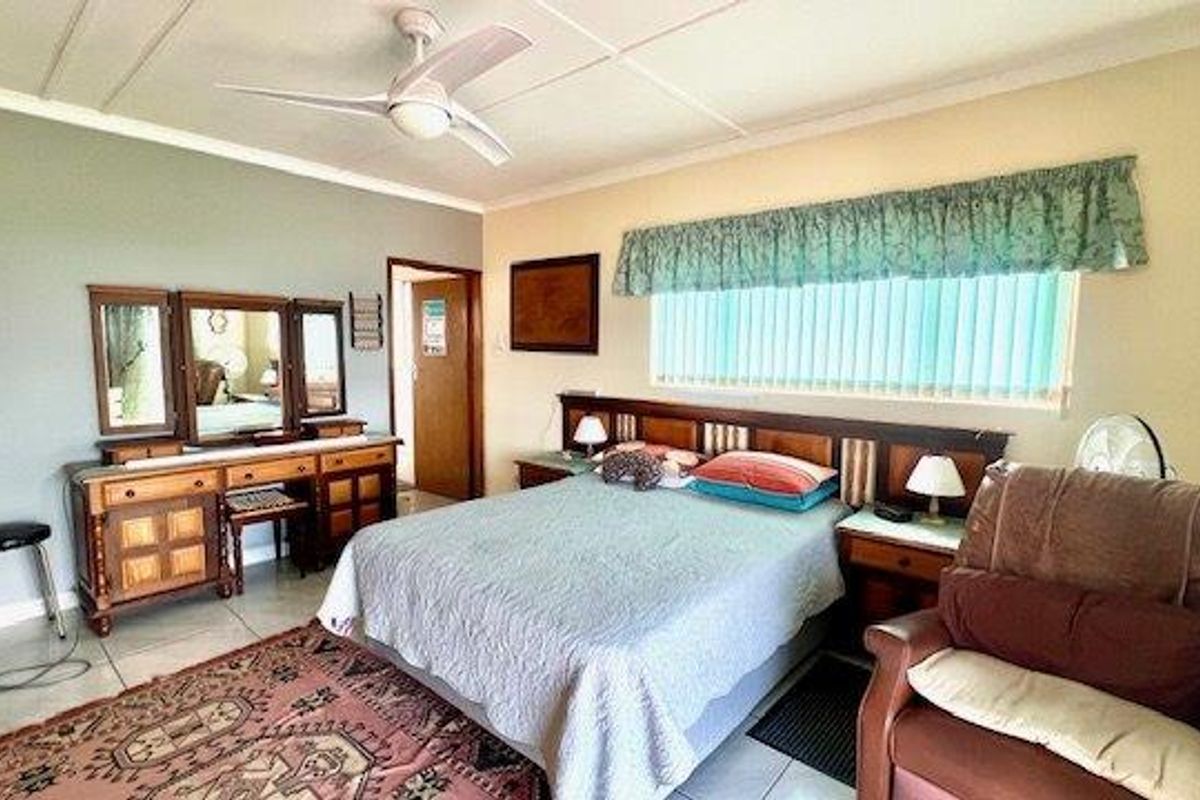 A bedroom featuring a ceiling fan, tiled flooring, and vertical window blinds.