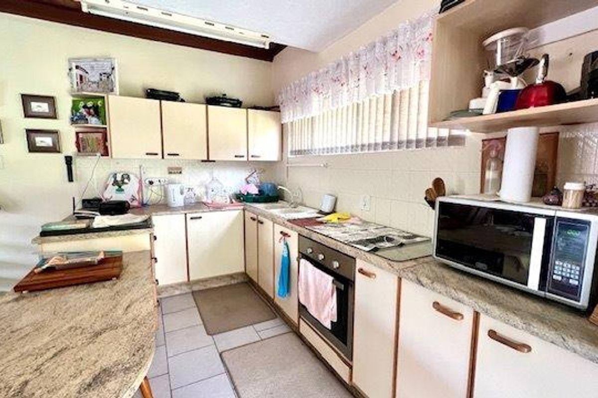A functional kitchen featuring laminate cabinetry, built-in oven, and a breakfast bar, offering a practical layout with ample counter space.