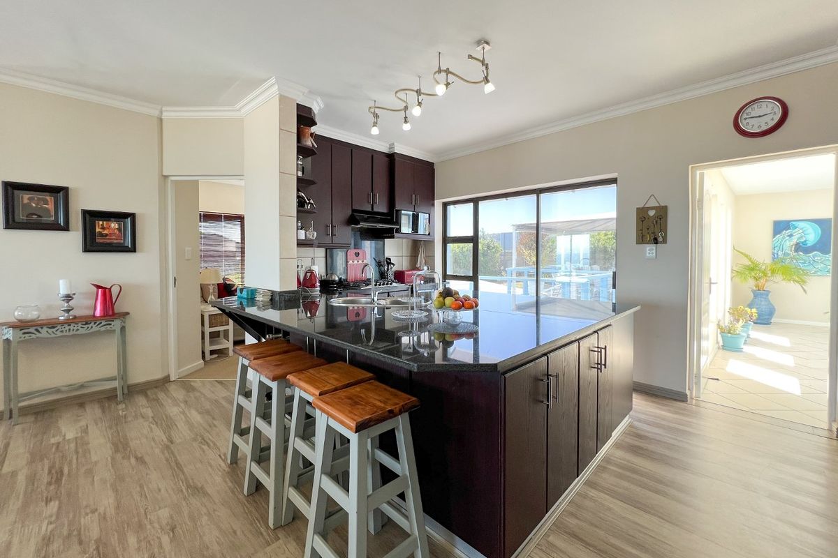 Modern kitchen featuring a large granite-topped island, dark wood cabinetry, and direct access to the outdoor patio area through sliding glass doors.