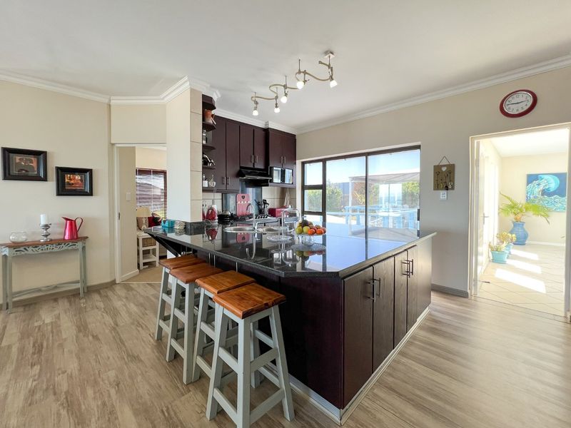 Modern kitchen featuring a large granite-topped island, dark wood cabinetry, and direct access to the outdoor patio area through sliding glass doors.