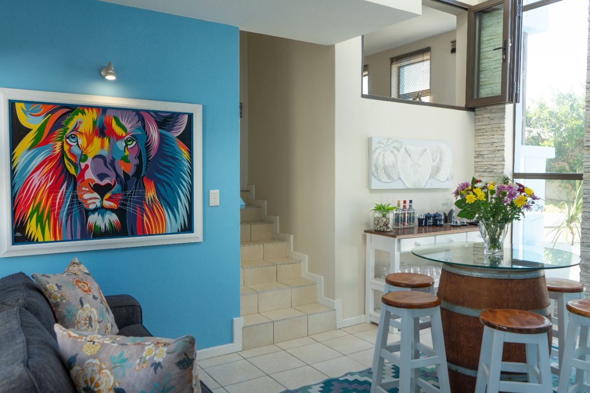 A bright living area featuring tiled flooring, a stone accent wall, and a staircase leading to an upper level with an internal window.