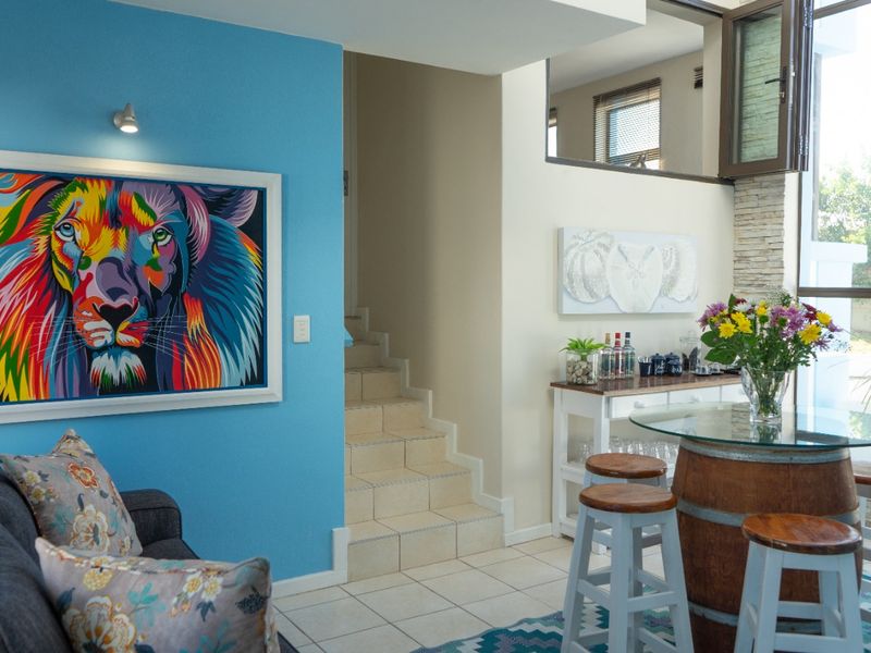 A bright living area featuring tiled flooring, a stone accent wall, and a staircase leading to an upper level with an internal window.