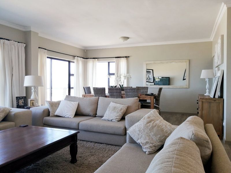 Spacious open-plan living and dining area featuring neutral tones, laminate flooring, and large sliding glass doors providing ample natural light.