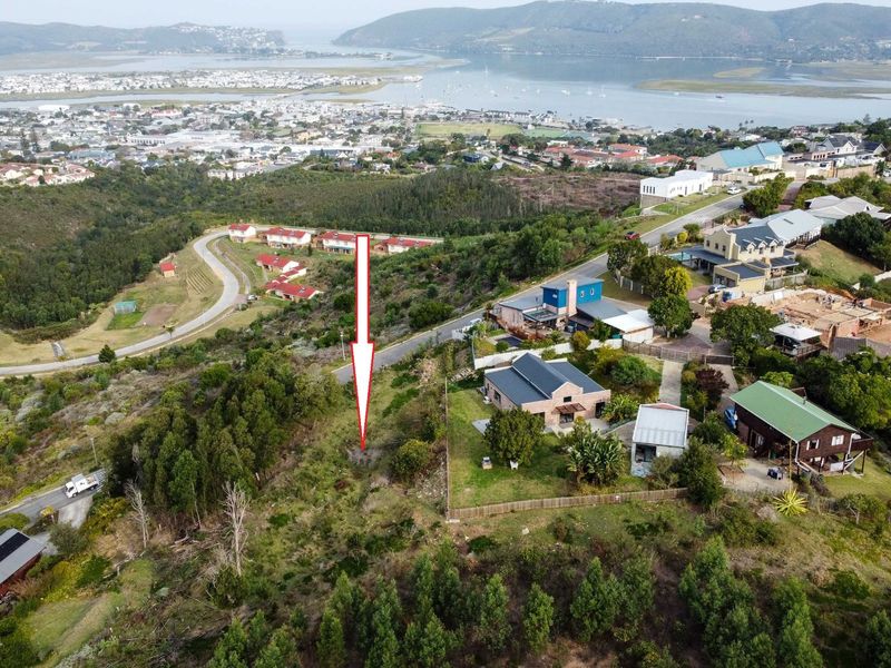 An aerial view of a vacant residential plot situated on a hillside, offering panoramic views of the surrounding town and estuary.