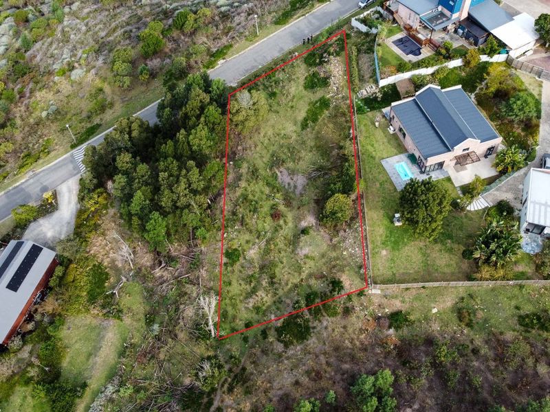 An aerial view of a vacant residential plot of land, clearly outlined in red, situated within a developed neighborhood.