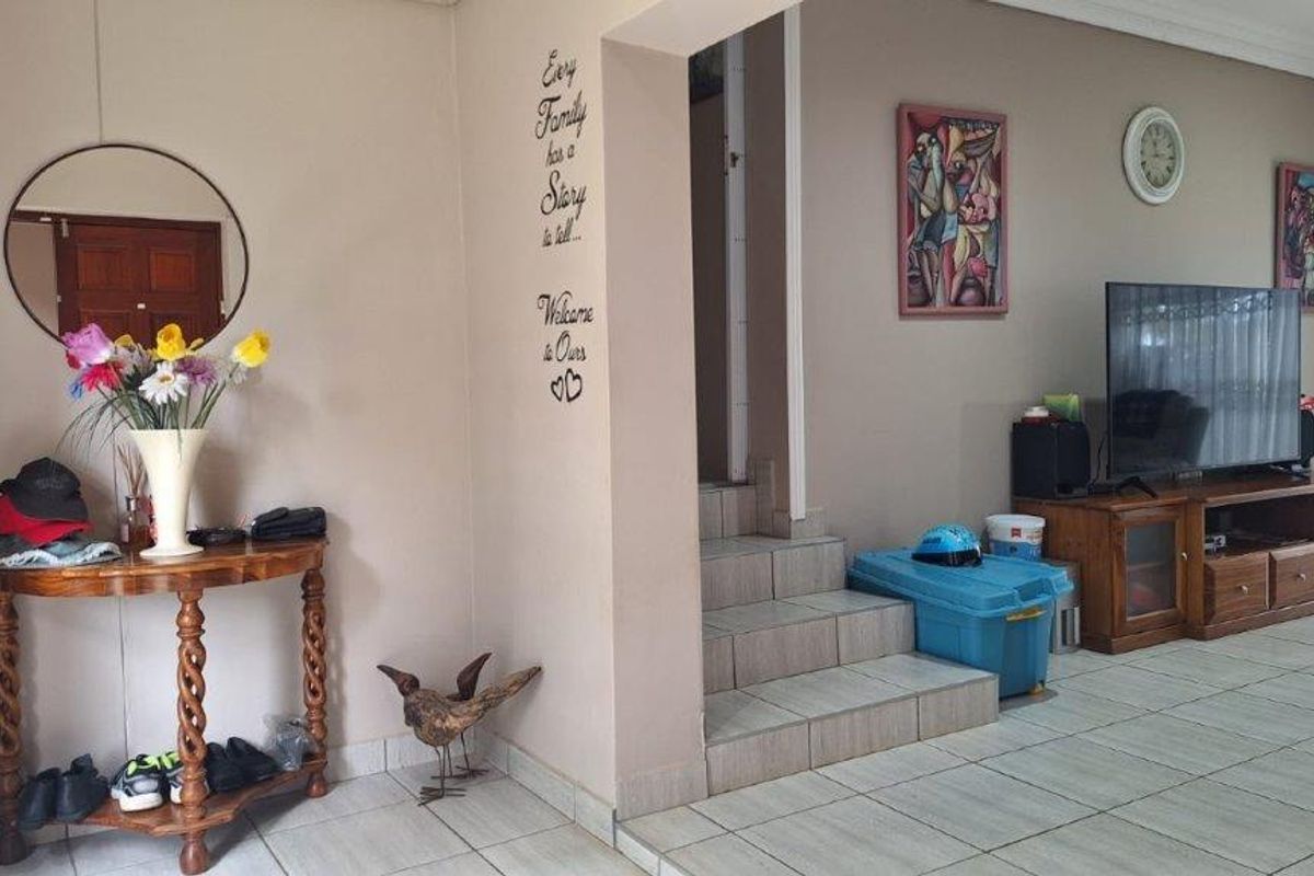 A living area featuring tiled flooring, an internal staircase, and an open archway connecting to adjacent spaces.