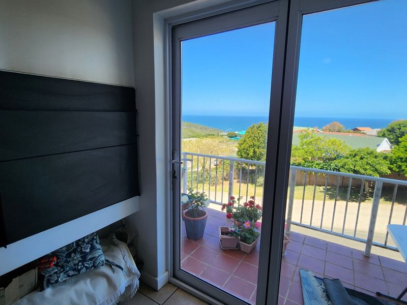A bright balcony area featuring tiled flooring and a metal balustrade, offering clear views of the surrounding landscape and ocean.