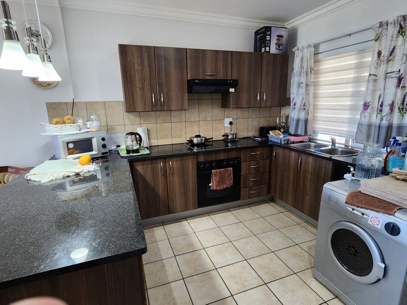 Functional kitchen featuring dark wood cabinetry, granite countertops, built-in oven with hob, and tiled flooring, providing a practical workspace for daily cooking.