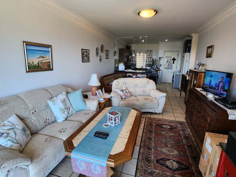 Open-plan living area featuring tiled flooring and a connected kitchen space, offering a functional layout for daily living.