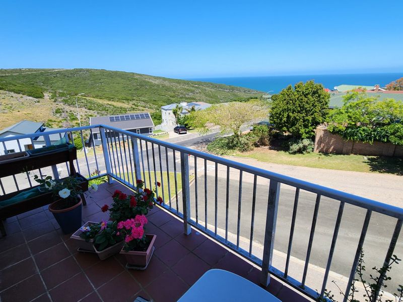 A balcony featuring a metal balustrade and tiled flooring, offering expansive views of the surrounding landscape and coastline.