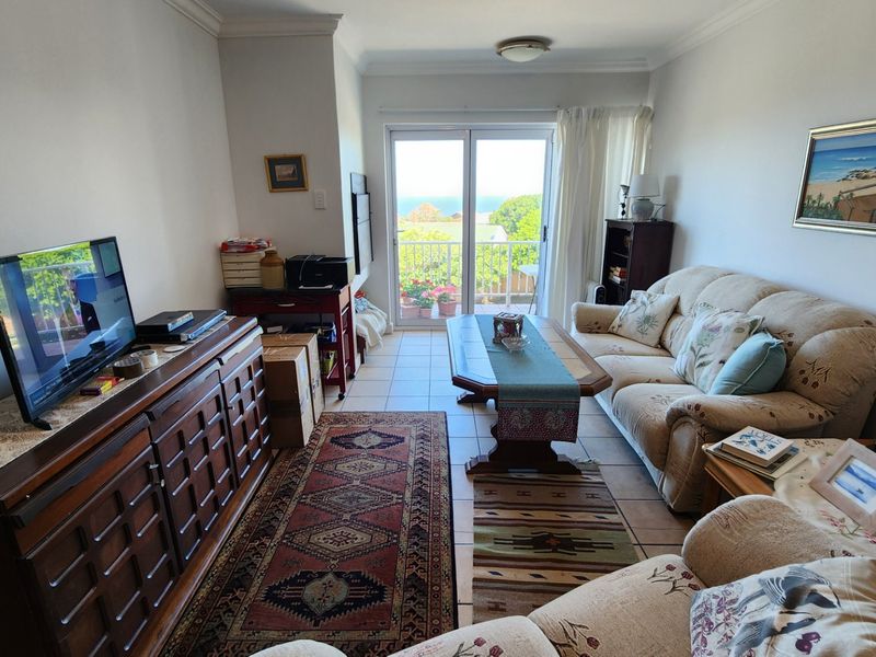 A comfortable living room featuring ceramic tile flooring and a sliding glass door that opens to a balcony with scenic views.