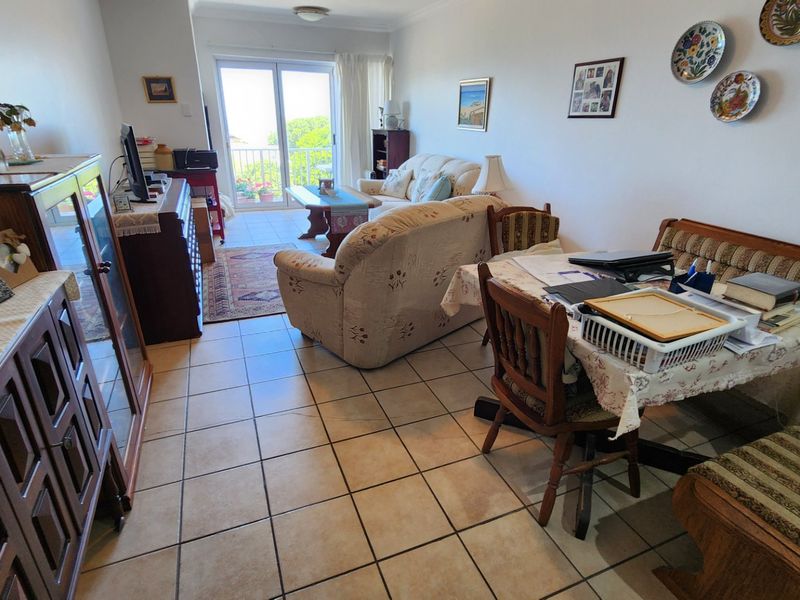 Open-plan living and dining area featuring ceramic floor tiles and direct access to a balcony through sliding glass doors.