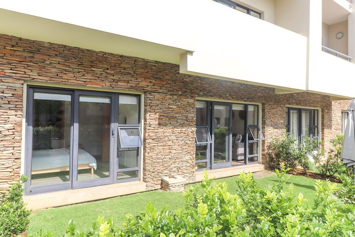 Ground floor apartment exterior featuring stone cladding, modern aluminium sliding doors, and direct access to a private garden area.