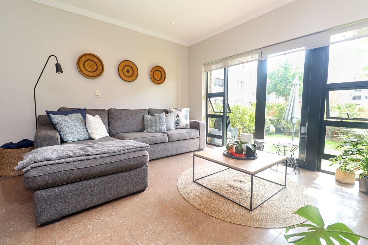 A bright living room featuring tiled flooring, recessed downlights, and large sliding glass doors that provide direct access to the outdoor area.