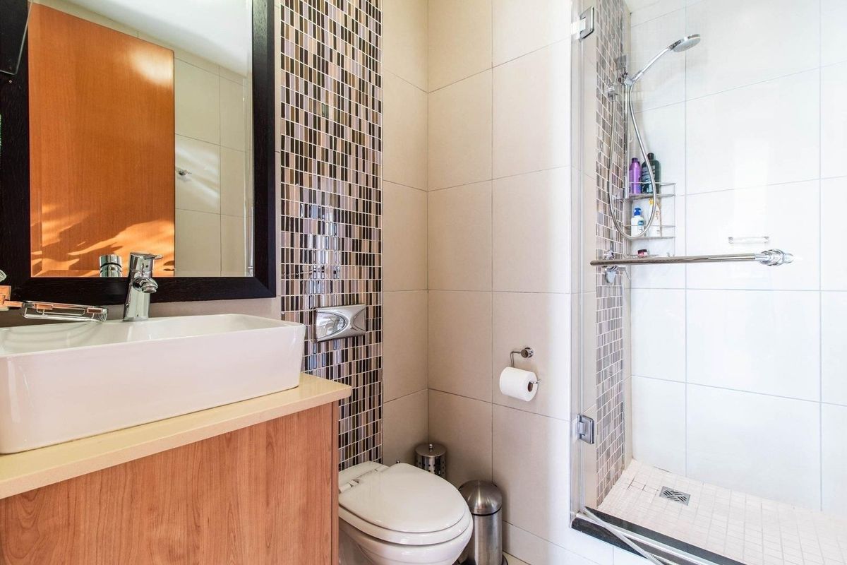 Modern bathroom featuring a vessel sink vanity, mosaic tile accents, and a glass-enclosed shower with a handheld shower head.