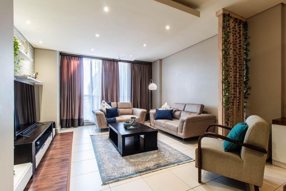 A well-maintained living room featuring tiled floors, recessed ceiling lighting, a decorative stone feature wall, and a timber slat room divider.