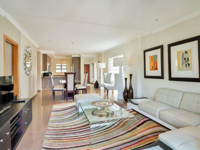 Spacious open-plan living and dining area featuring tiled flooring, recessed lighting, and a modern kitchen with integrated cabinetry.