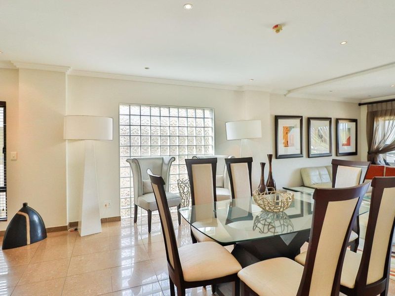 Spacious open-plan living and dining area featuring tiled flooring, recessed lighting, and a distinctive glass block feature window.