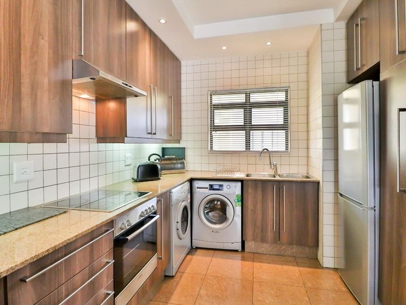 Modern kitchen featuring wood-finish cabinetry, stone countertops, integrated appliances, tiled splashbacks, and recessed lighting in a functional, well-maintained layout.