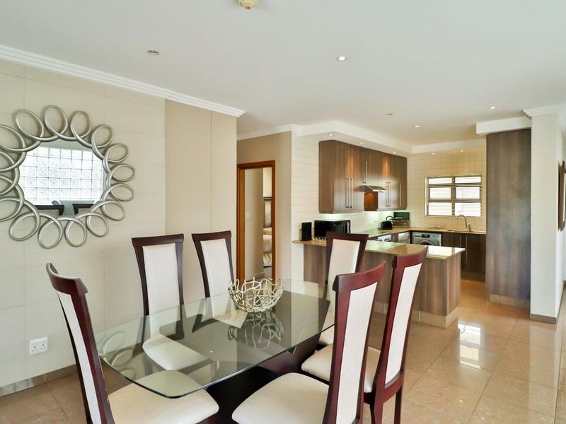 Open-plan living and dining area featuring a modern kitchen with built-in cabinetry, a breakfast island, and tiled flooring throughout.