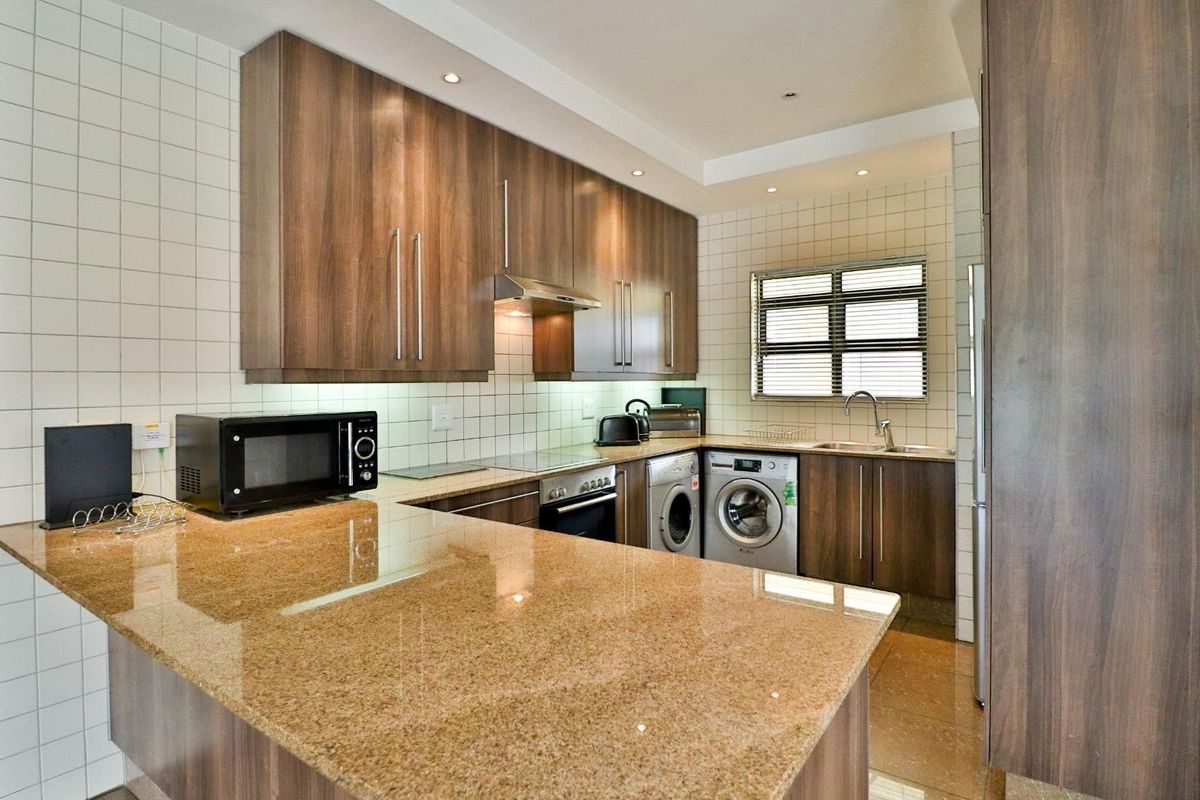 Modern kitchen featuring wood-finish cabinetry, granite countertops, integrated appliances, and a tiled backsplash, offering a functional and well-maintained cooking space.