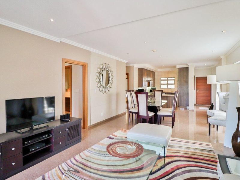 Spacious open-plan living and dining area featuring tiled floors, recessed lighting, and a seamless flow into the modern kitchen space.