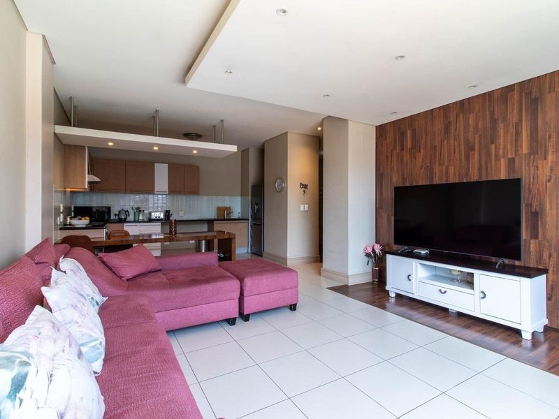 Spacious open-plan living area featuring a modern kitchen with built-in cabinetry, tiled floors, and a striking wood-paneled feature wall.