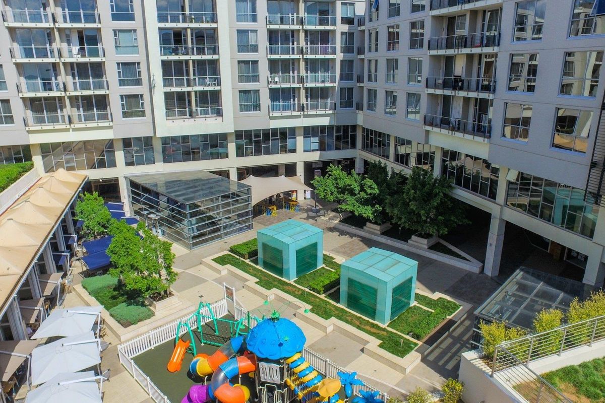 Aerial view of the apartment complex courtyard featuring landscaped gardens, glass skylights, and paved communal areas.