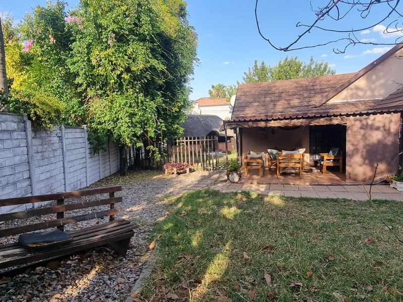 A rear garden view featuring a paved patio area, lawn, and precast concrete boundary wall, providing a private outdoor space for the property.