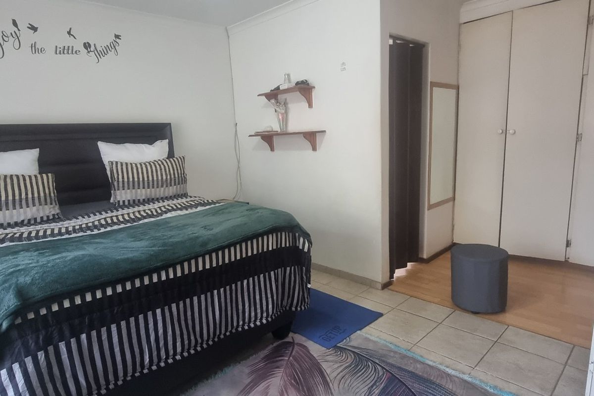 A bedroom featuring a mix of tiled and laminate flooring, built-in cupboards, and coving detail.