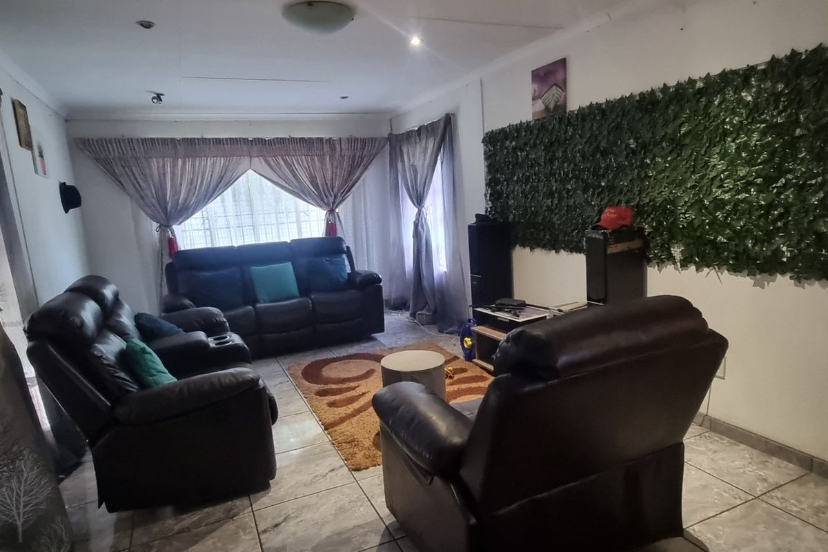 A living room featuring tiled flooring, recessed lighting, and sliding glass doors, providing a functional space with potential for cosmetic updates.