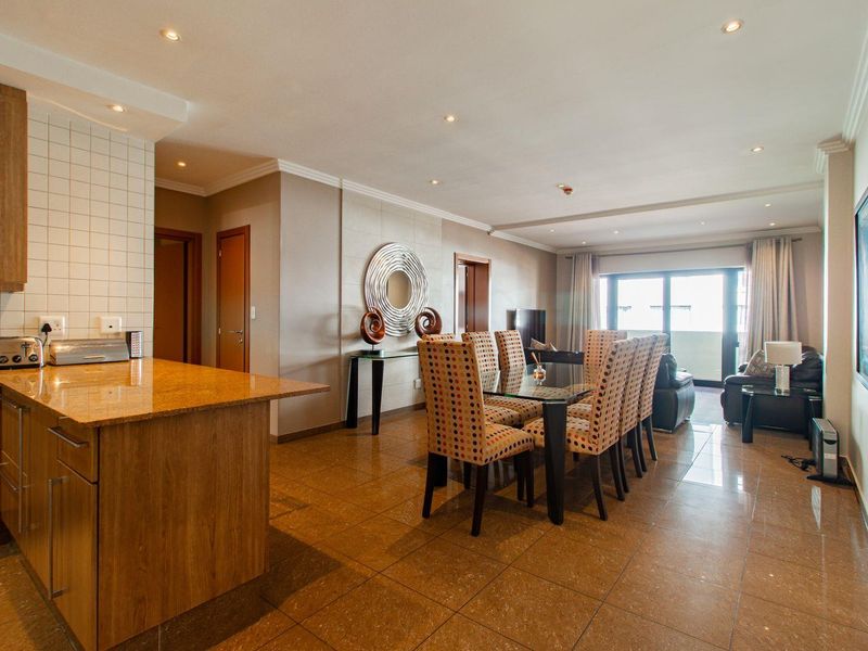 Spacious open-plan living and dining area featuring tiled flooring, recessed lighting, and a functional kitchen with granite countertops and wood cabinetry.