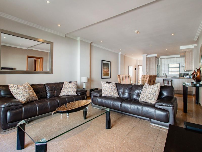 Spacious open-plan living area featuring tiled flooring, recessed lighting, and a functional kitchen with built-in cabinetry and a tiled backsplash.