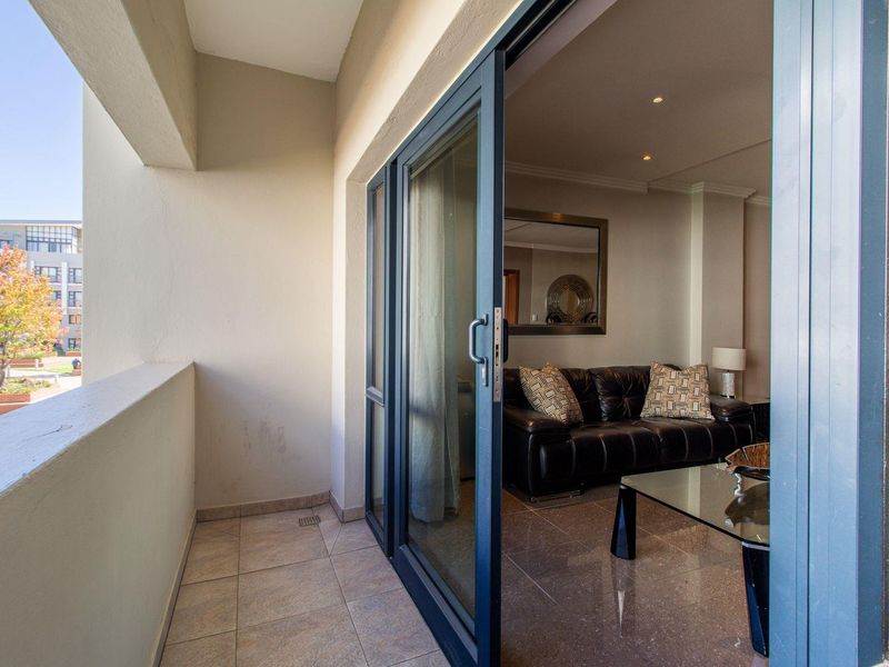 A covered balcony with tiled flooring and sliding glass doors providing access to the interior living area.