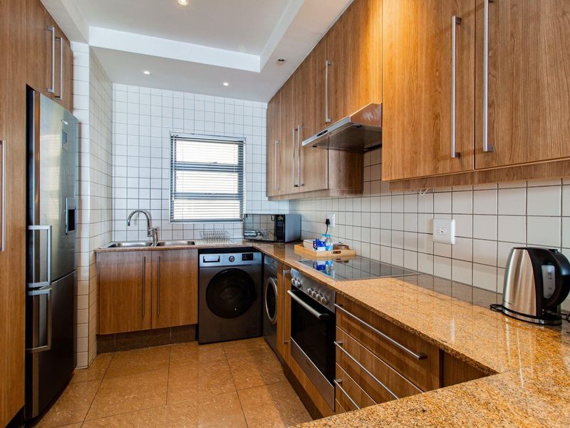 A well-maintained kitchen featuring wood-veneer cabinetry, granite countertops, a tiled backsplash, and integrated stainless steel appliances.