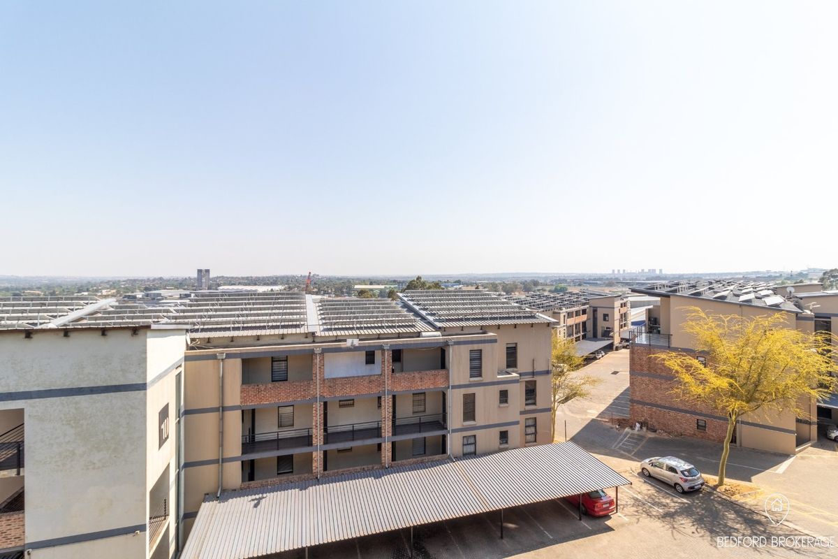 An aerial view of the apartment complex featuring covered parking bays and solar panel installations on the roof.