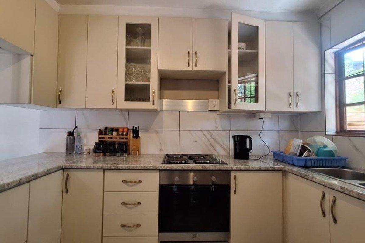 A functional kitchen featuring light-toned cabinetry, marble-look countertops, a built-in oven with gas hob, and a tiled backsplash.