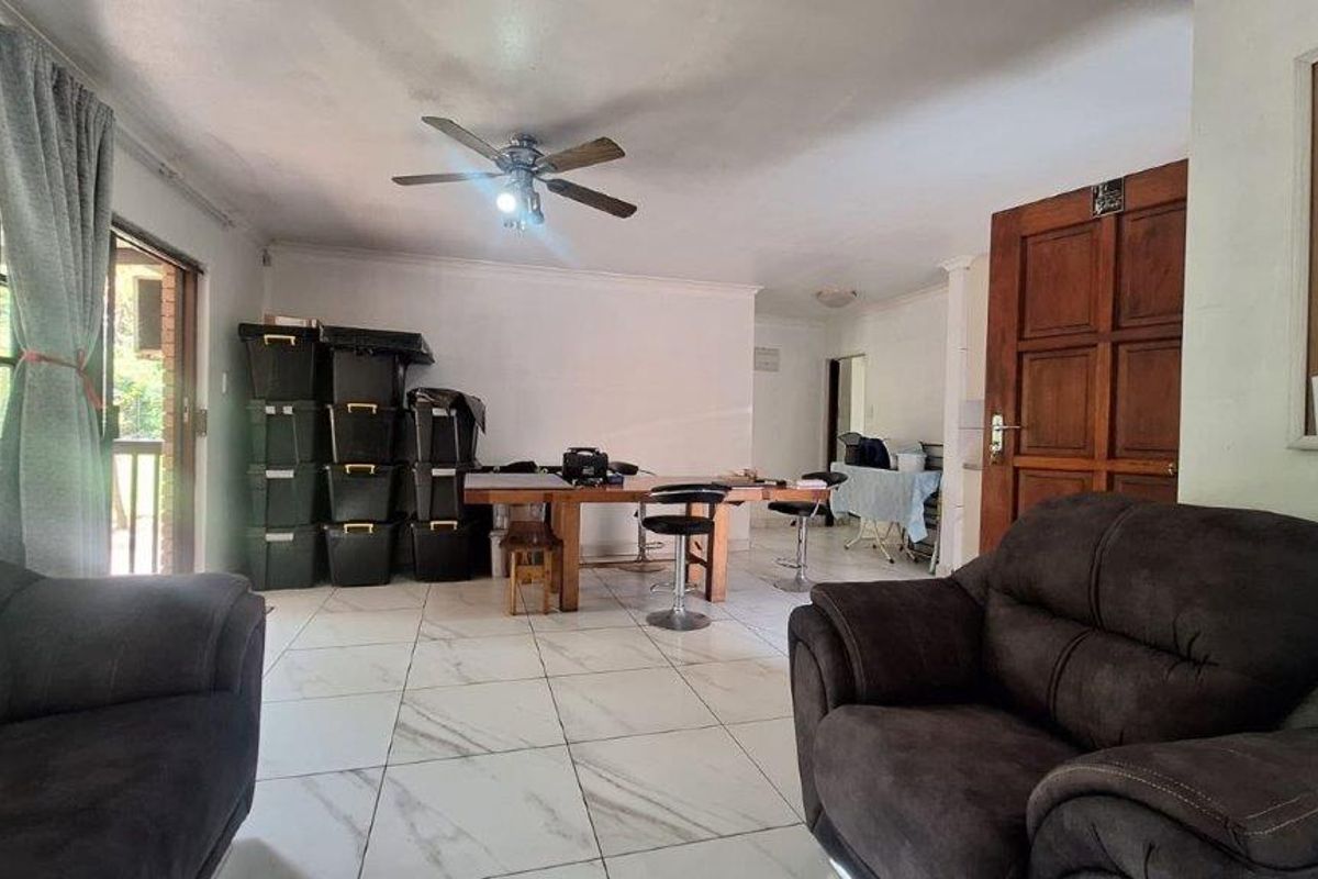 Spacious living area featuring tiled flooring, a ceiling fan, and direct access to an outdoor patio through sliding glass doors.