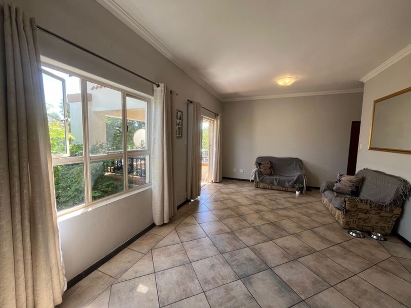 Spacious living room featuring large windows, tiled flooring, and direct access to an outdoor area, offering a bright and functional living space.
