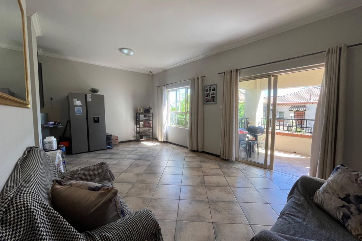 Spacious living room featuring tiled flooring and large sliding glass doors that provide direct access to an outdoor balcony area.