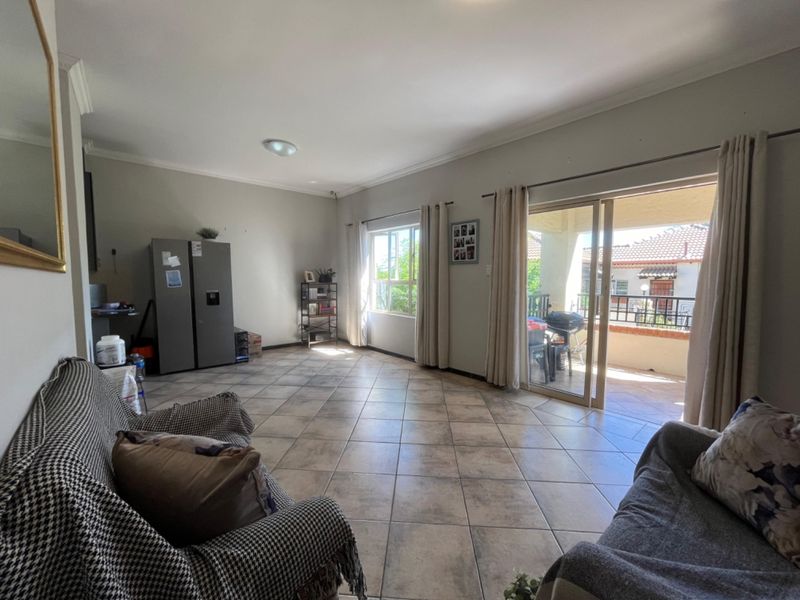 Spacious living room featuring tiled flooring and large sliding glass doors that provide direct access to an outdoor balcony area.