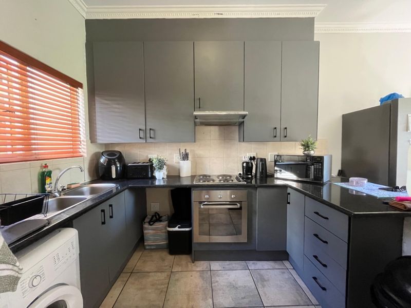 A functional kitchen featuring dark grey cabinetry, granite countertops, stainless steel appliances, and tiled flooring, offering a clean and practical workspace.