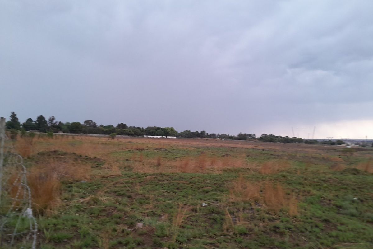 A wide, undeveloped residential plot of land featuring natural grass cover and a perimeter barbed wire fence.