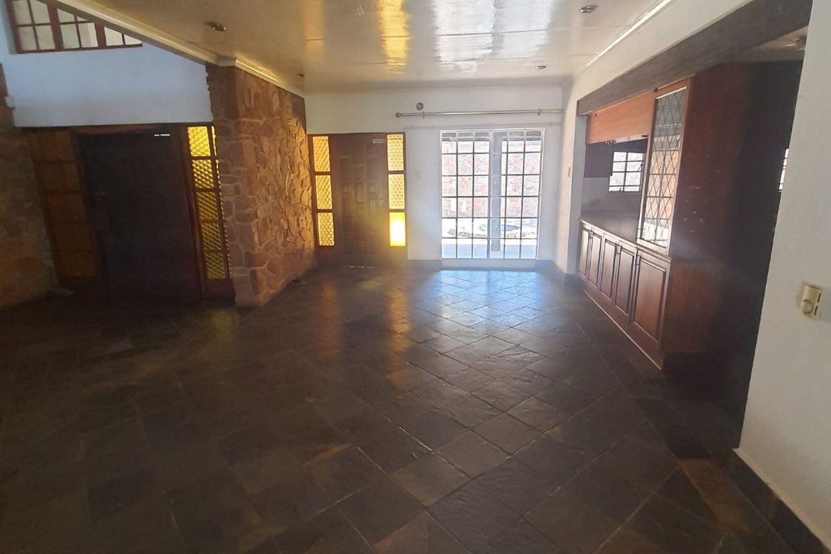 Spacious living area featuring natural slate tile flooring, a rustic stone feature wall, and built-in wooden cabinetry, offering a solid foundation for renovation.