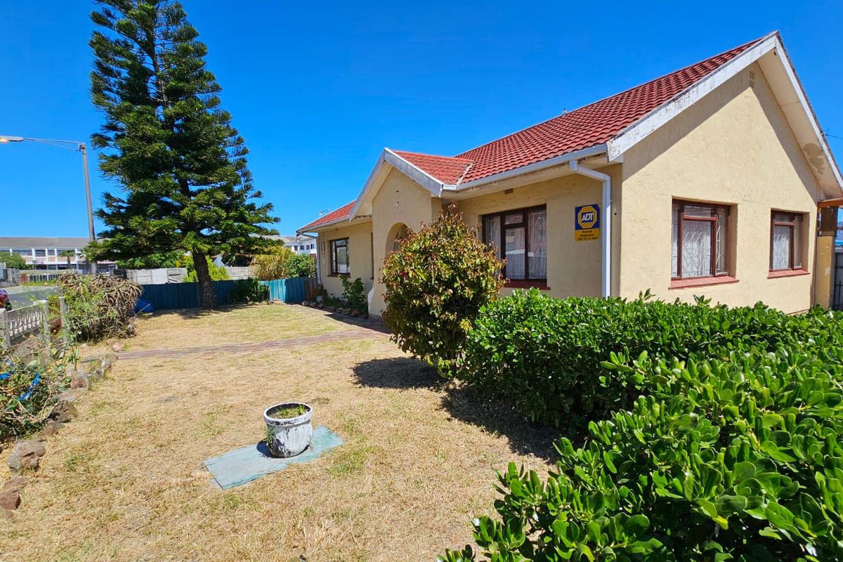 Front view of a residential property featuring a tiled roof, security bars on windows, and a front garden area.