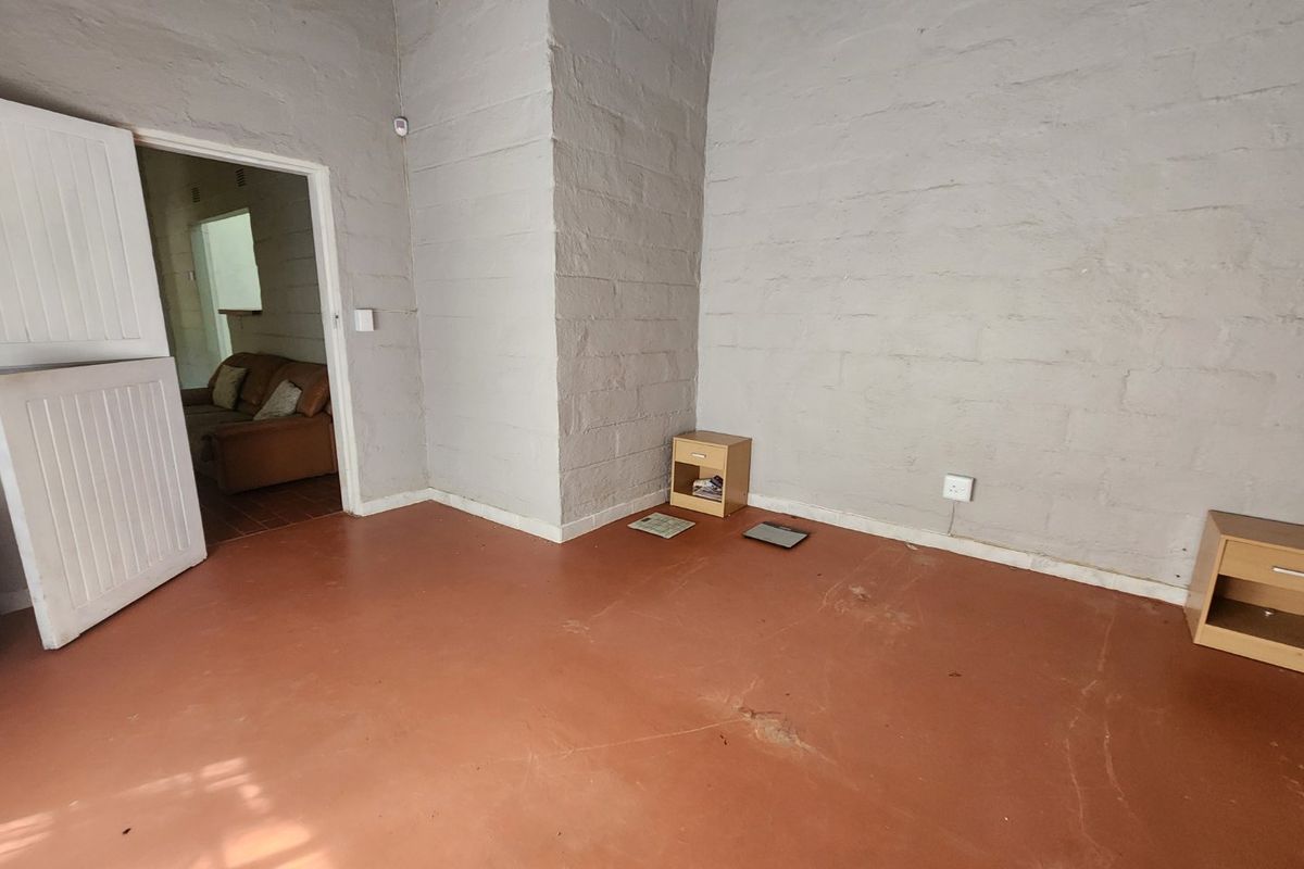 An empty bedroom featuring painted brick walls and a painted concrete floor, offering a blank canvas for renovation or interior design.