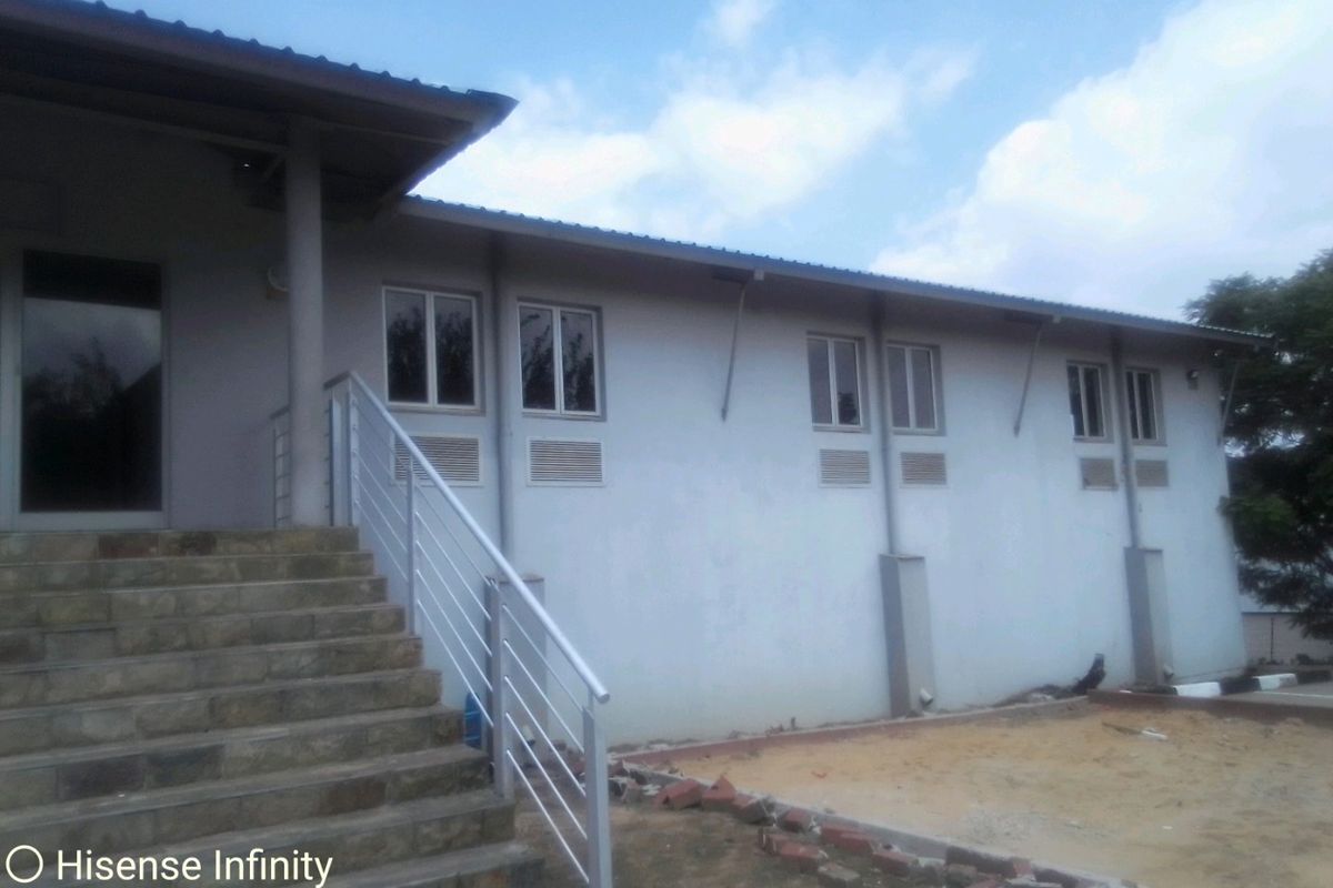 Exterior view of a commercial building featuring a stone staircase, metal balustrade, and multiple windows with wall-mounted air conditioning units.