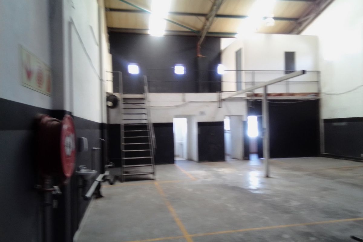 Spacious industrial utility area featuring a mezzanine level, metal staircase, concrete flooring, and high-clearance exposed roof structure.